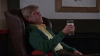 Movie still from “Creepshow” (1982), directed by George A. Romero – A man sitting in a chair holding a glass of beer; Medium shot, Low angle