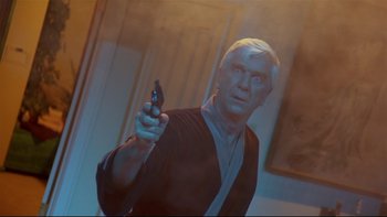 Movie still from “Creepshow” (1982), directed by George A. Romero – An older man holding a gun while wearing a robe; Medium shot, Low angle