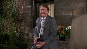 Movie still from “Creepshow” (1982), directed by George A. Romero – A man in a suit and tie holding a coffee cup; Medium shot, Over the shoulder angle
