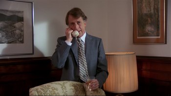 Movie still from “Creepshow” (1982), directed by George A. Romero – A man wearing a suit and tie talking on a phone; Medium shot, High angle