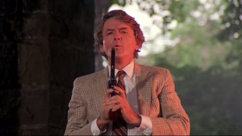 Movie still from “Creepshow” (1982), directed by George A. Romero – A man in a suit and tie holding a pipe; Medium shot, Low angle
