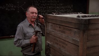 Movie still from “Creepshow” (1982), directed by George A. Romero – An older man holding a hammer in front of a blackboard; Medium shot, High angle