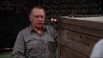 Movie still from “Creepshow” (1982), directed by George A. Romero – An older man holding a wrench near a wooden box; Close Up shot, High angle