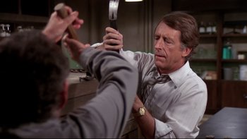 Movie still from “Creepshow” (1982), directed by George A. Romero – A man holding a knife in his hand while another man holds it up; Medium shot, Over the shoulder angle