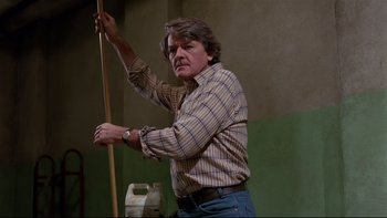 Movie still from “Creepshow” (1982), directed by George A. Romero – A man holding a broom in his hand; Medium shot, Low angle