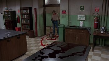 Movie still from “Creepshow” (1982), directed by George A. Romero – A man is standing in a room next to a blood puddle; Wide shot, High angle