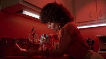 Movie still from “Creepshow” (1982), directed by George A. Romero – A woman sitting at a table looking at a cell phone; Medium shot, Low angle