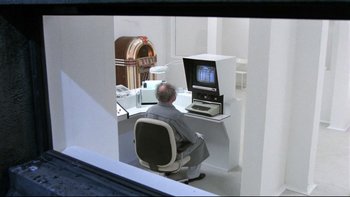 Movie still from “Creepshow” (1982), directed by George A. Romero – An older man sitting at a computer desk; Wide shot, High angle