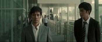 A man in a gray suit standing in front of some stairs
