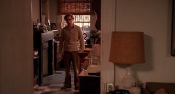 Movie still from “Crimes and Misdemeanors” (1989), directed by Woody Allen – A man standing in a room with a vase on the floor; Wide shot, Over the shoulder angle