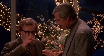 Movie still from “Crimes and Misdemeanors” (1989), directed by Woody Allen – Two men standing next to each other holding wine glasses; Medium shot, Over the shoulder angle