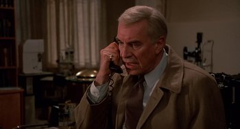 Movie still from “Crimes and Misdemeanors” (1989), directed by Woody Allen – An older man talking on a phone while wearing a suit and tie; Close Up shot, High angle
