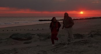 Movie still from “Crimes and Misdemeanors” (1989), directed by Woody Allen – A man and a woman running on the beach at sunset; Wide shot, High angle