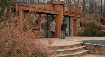 Movie still from “Crimes and Misdemeanors” (1989), directed by Woody Allen – Two men standing in front of a wooden building; Wide shot, Low angle