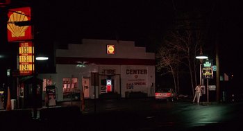 Movie still from “Crimes and Misdemeanors” (1989), directed by Woody Allen – A car parked in front of a tire center; Extreme Wide shot, High angle