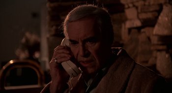 Movie still from “Crimes and Misdemeanors” (1989), directed by Woody Allen – An older man talking on a phone while wearing headphones; Close Up shot, Low angle
