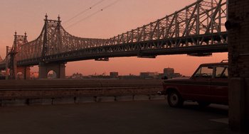 Movie still from “Crimes and Misdemeanors” (1989), directed by Woody Allen – A car is parked on the side of the road under a bridge; Extreme Wide shot, Low angle