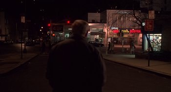 Movie still from “Crimes and Misdemeanors” (1989), directed by Woody Allen – A man standing on the side of the street at night; Wide shot, Over the shoulder angle