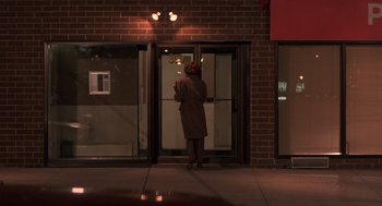 Movie still from “Crimes and Misdemeanors” (1989), directed by Woody Allen – A person standing in front of a building at night; Wide shot, Low angle