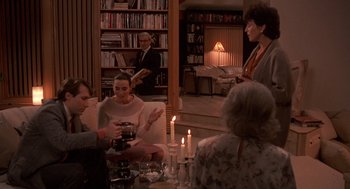 Movie still from “Crimes and Misdemeanors” (1989), directed by Woody Allen – A group of people sitting around a living room table; Wide shot, High angle