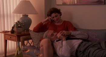 Movie still from “Crimes and Misdemeanors” (1989), directed by Woody Allen – An older man and a younger woman sitting on a couch; Medium shot, High angle