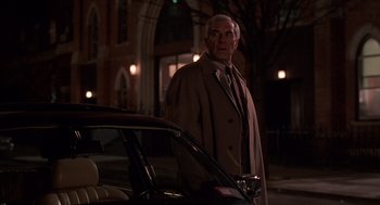 Movie still from “Crimes and Misdemeanors” (1989), directed by Woody Allen – An older man standing next to a parked car at night; Medium shot, Low angle