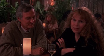 Movie still from “Crimes and Misdemeanors” (1989), directed by Woody Allen – A man and a woman sitting at a table with a glass of wine; Medium shot, Over the shoulder angle