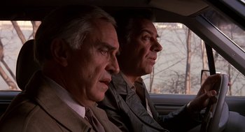 Movie still from “Crimes and Misdemeanors” (1989), directed by Woody Allen – Two older men sitting in the back seat of a car; Close Up shot, Low angle