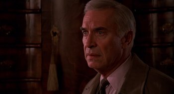 Movie still from “Crimes and Misdemeanors” (1989), directed by Woody Allen – An older man wearing a suit and tie looking at the camera; Close Up shot, Over the shoulder angle