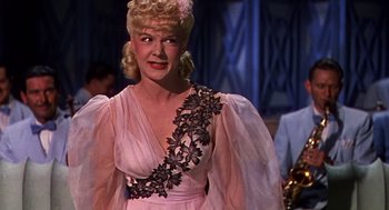 Movie still from “Crimes and Misdemeanors” (1989), directed by Woody Allen – A woman wearing a pink dress with black flowers on it; Close Up shot, Low angle