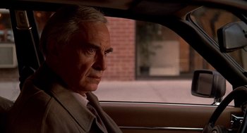Movie still from “Crimes and Misdemeanors” (1989), directed by Woody Allen – An older man sitting in the back seat of a car; Close Up shot, Over the shoulder angle