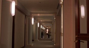 Movie still from “Crimes and Misdemeanors” (1989), directed by Woody Allen – Two people are standing in a long hallway with lights on; Extreme Wide shot, Over the shoulder angle