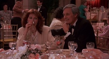 Movie still from “Crimes and Misdemeanors” (1989), directed by Woody Allen – A man and a woman sitting at a dinner table drinking wine; Medium shot, Over the shoulder angle
