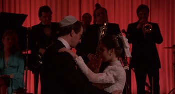 Movie still from “Crimes and Misdemeanors” (1989), directed by Woody Allen – A man and a woman are dancing in front of an orchestra; Medium shot, Over the shoulder angle