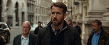 Movie still from “Criminal” (2016), directed by Ariel Vromen – A person walking on a city street; Close Up shot, Over the shoulder angle