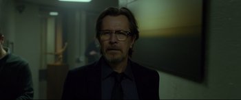 Movie still from “Criminal” (2016), directed by Ariel Vromen – A person wearing a suit and glasses; Medium shot, Low angle