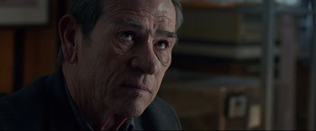 Movie still from “Criminal” (2016), directed by Ariel Vromen – An older man with a serious look on his face; Close Up shot, Over the shoulder angle