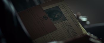 Movie still from “Criminal” (2016), directed by Ariel Vromen – An old photo of a man's face on top of an old document; Extreme Close Up shot, Overhead angle