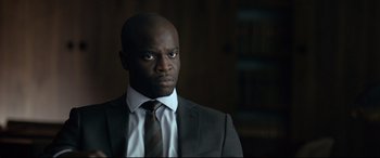 Movie still from “Criminal” (2016), directed by Ariel Vromen – A man in a suit and tie looking to his left; Close Up shot, Over the shoulder angle