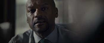 Movie still from “Criminal” (2016), directed by Ariel Vromen – A person wearing a suit and tie; Close Up shot, Low angle