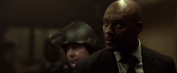 Movie still from “Criminal” (2016), directed by Ariel Vromen – A man in a black suit and a man in a brown suit; Close Up shot, Over the shoulder angle