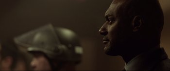Movie still from “Criminal” (2016), directed by Ariel Vromen – A man's face in a dark room; Close Up shot, Over the shoulder angle