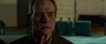 Movie still from “Criminal” (2016), directed by Ariel Vromen – An older man with a serious look on his face; Close Up shot, Over the shoulder angle