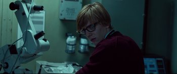 Movie still from “Criminal” (2016), directed by Ariel Vromen – A person with glasses sitting in a room; Medium shot, Over the shoulder angle
