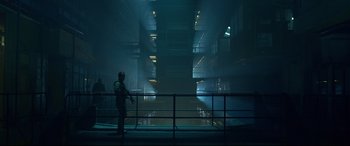 Movie still from “Criminal” (2016), directed by Ariel Vromen – A man standing in a dark room with a gun in his hand; Extreme Wide shot, Low angle