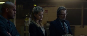 Movie still from “Criminal” (2016), directed by Ariel Vromen – A woman in a black jacket and a man in a black suit; Medium shot, Low angle