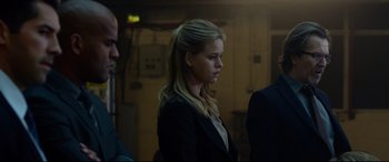 Movie still from “Criminal” (2016), directed by Ariel Vromen – A woman standing in a room next to two men; Medium shot, Low angle