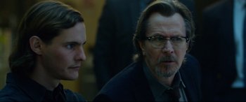 Movie still from “Criminal” (2016), directed by Ariel Vromen – A man in a suit and tie sitting next to another man in a suit and tie; Close Up shot, Over the shoulder angle