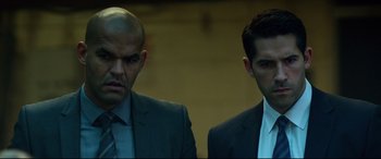 Movie still from “Criminal” (2016), directed by Ariel Vromen – Two men in business suits standing next to each other; Close Up shot, Low angle