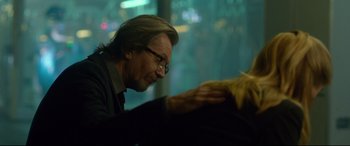 Movie still from “Criminal” (2016), directed by Ariel Vromen – A man holding a cat's paw while sitting in a chair; Close Up shot, Over the shoulder angle